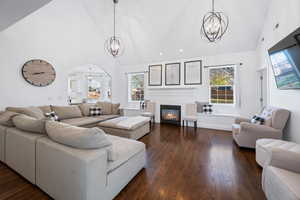 Living room with high vaulted ceiling, a chandelier, and dark hardwood / wood-style floors