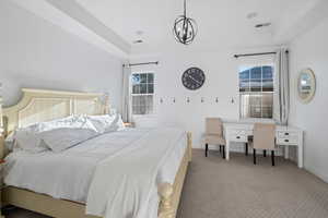 Bedroom featuring a chandelier, carpet floors, and a tray ceiling