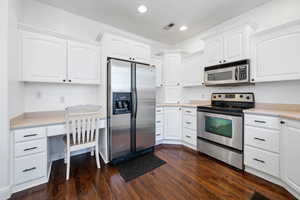 Kitchen featuring dark hardwood / wood-style floors, white cabinetry, and stainless steel appliances