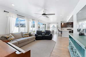 Living room with a textured ceiling, ceiling fan, sink, and light hardwood / wood-style flooring