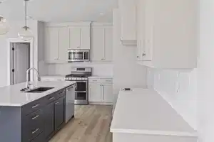 Kitchen featuring white cabinets, decorative light fixtures, stainless steel appliances, and sink