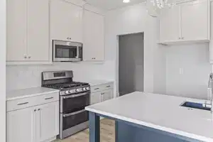 Kitchen with backsplash, decorative light fixtures, white cabinetry, and stainless steel appliances