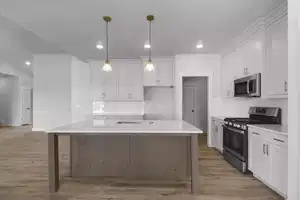 Kitchen featuring a kitchen island with sink, white cabinetry, and stainless steel appliances