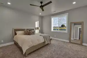 Carpeted bedroom featuring ceiling fan and a textured ceiling