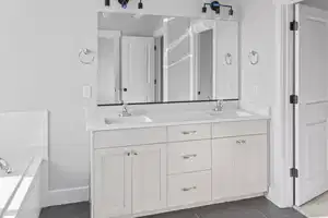 Bathroom featuring tile patterned flooring, vanity, and a tub to relax in