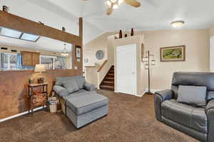 Carpeted living room featuring ceiling fan and vaulted ceiling