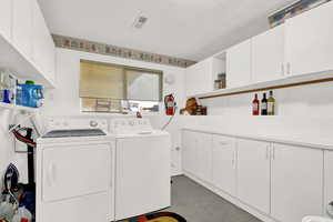 Spacious laundry room with lots of cabinets, washer and dryer stay