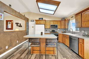 Kitchen featuring a center island with seating, vaulted ceiling