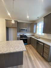 Pictures are for reference only and not of actual unit. Kitchen featuring appliances with stainless steel finishes, light hardwood / wood-style floors, pendant lighting, and sink