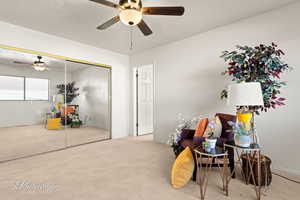 Living area with light carpet and ceiling fan