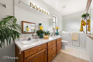 Bathroom featuring tile patterned flooring, vanity, toilet, and a textured ceiling