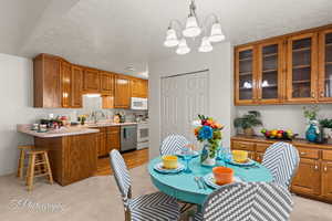 Kitchen with sink, kitchen peninsula, light colored carpet, pendant lighting, and white appliances