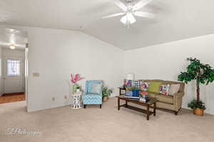 Living area with ceiling fan, lofted ceiling, and light carpet