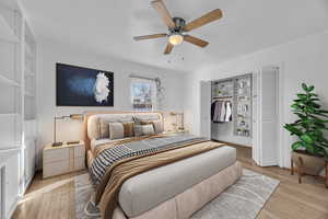 Bedroom featuring light hardwood flooring, a roomy closet, shelving and ceiling fan