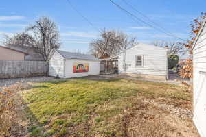 Rear view of backyard with garage and storage shed, beds for gardening