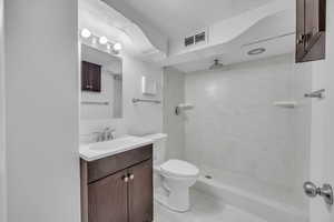 Bathroom featuring vanity, tile patterned floors, toilet, and a tile shower