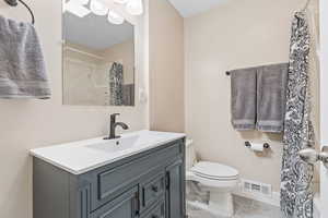 Bathroom featuring tile patterned floors, a shower with curtain, vanity, and toilet