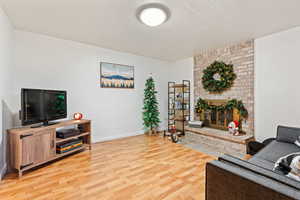 Living room featuring hardwood / wood-style floors, a textured ceiling, and a brick fireplace