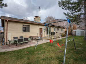 Back of house with a lawn, a patio, and a shed