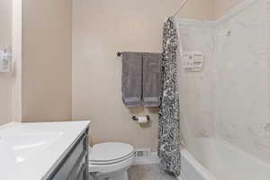 Full bathroom with tile patterned floors, vanity, shower / bath combo, and toilet