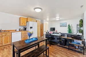 Kitchen with a textured ceiling, sink, light hardwood / wood-style floors, and white appliances