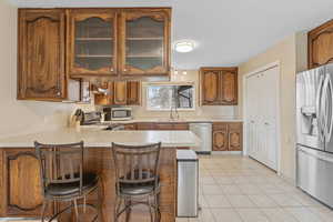 Kitchen with a breakfast bar, sink, light tile patterned floors, kitchen peninsula, and stainless steel appliances