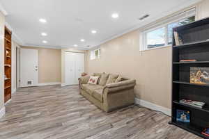 Living room with hardwood / wood-style floors, ornamental molding, and wood walls