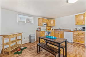 Kitchen with sink, light brown cabinets, light hardwood / wood-style floors, a textured ceiling, and white appliances