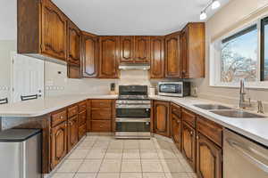 Kitchen featuring kitchen peninsula, a textured ceiling, stainless steel appliances, sink, and light tile patterned flooring