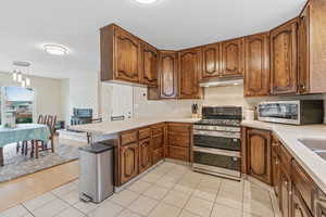 Kitchen with kitchen peninsula, appliances with stainless steel finishes, light hardwood / wood-style floors, and hanging light fixtures