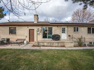 Back of property with solar panels, a yard, and a patio. BACK PRIVATE BASEMENT APARTMENT ENTRANCE !