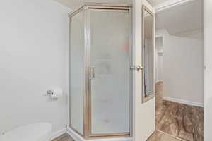 Bathroom featuring hardwood / wood-style flooring, toilet, and walk in shower