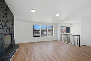 Unfurnished living room with a fireplace, light hardwood / wood-style flooring, and lofted ceiling