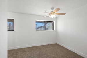 Spare room featuring carpet, a textured ceiling, and ceiling fan