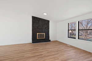 Unfurnished living room featuring light hardwood / wood-style floors, a fireplace, and heating unit