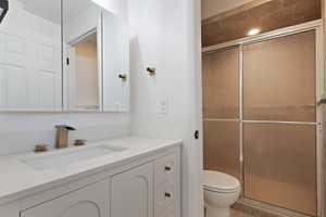 Bathroom featuring toilet, vanity, and walk in shower