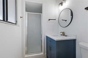 Bathroom with vanity, toilet, and a shower with shower door