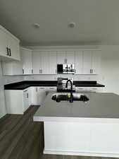 Kitchen with a textured ceiling, white cabinetry, dark hardwood / wood-style floors, and appliances with stainless steel finishes