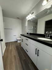 Bathroom featuring walk in shower, a textured ceiling, toilet, vanity, and hardwood / wood-style flooring