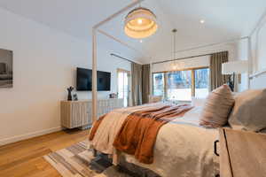 Bedroom featuring an inviting chandelier, light hardwood / wood-style flooring, and lofted ceiling