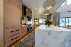 Kitchen featuring wall chimney range hood, plenty of natural light, light hardwood / wood-style flooring, and range with two ovens