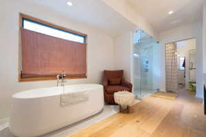 Bathroom with hardwood / wood-style floors and shower with separate bathtub