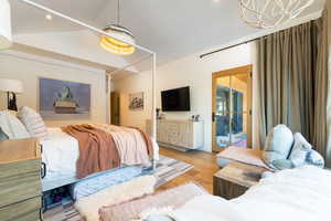 Bedroom with access to exterior, light hardwood / wood-style flooring, lofted ceiling, and a notable chandelier