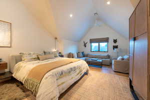 Bedroom with ceiling fan, light wood-type flooring, and vaulted ceiling