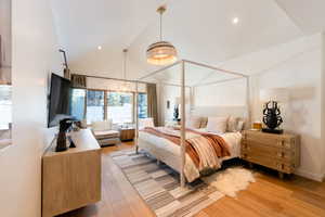 Bedroom featuring vaulted ceiling, light hardwood / wood-style flooring, and a notable chandelier