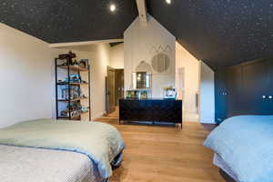 Bedroom featuring hardwood / wood-style flooring, beam ceiling, and high vaulted ceiling