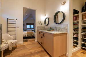 Bathroom with hardwood / wood-style floors, vanity, vaulted ceiling, and ceiling fan