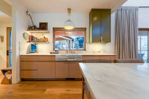 Kitchen featuring decorative light fixtures, green cabinets, a wealth of natural light, and light hardwood / wood-style flooring