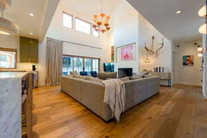 Living room featuring plenty of natural light, light wood-type flooring, a towering ceiling, and a chandelier