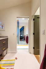 Bathroom featuring hardwood / wood-style floors, vanity, and lofted ceiling